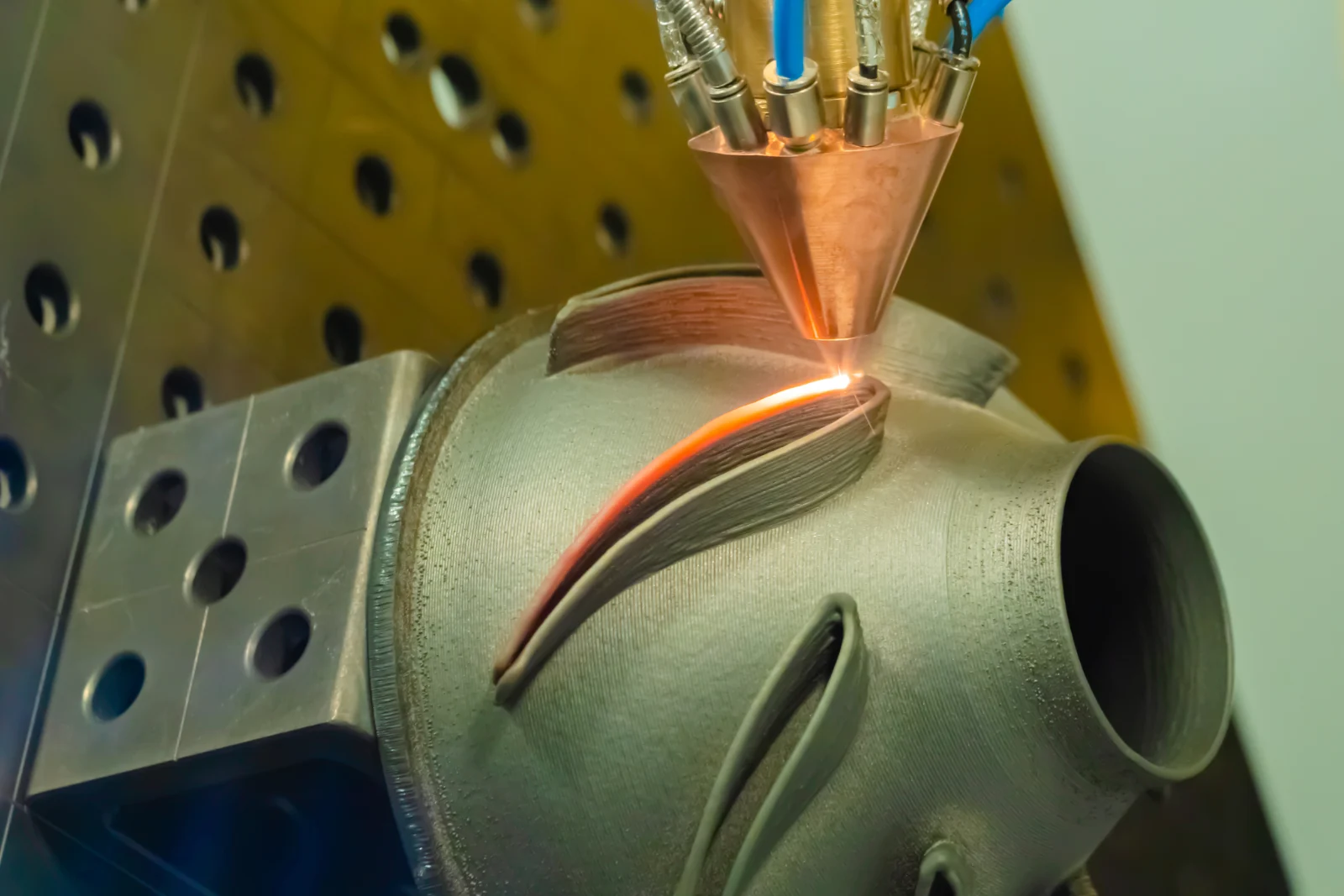 Laser metal deposition nozzle fusing metal powder onto a turbine housing
