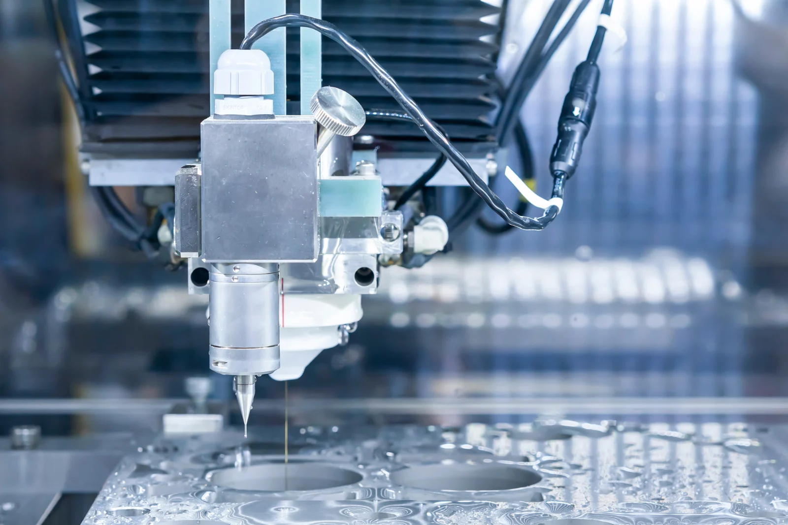 Wire EDM machine cutting profiles through a submerged metal plate