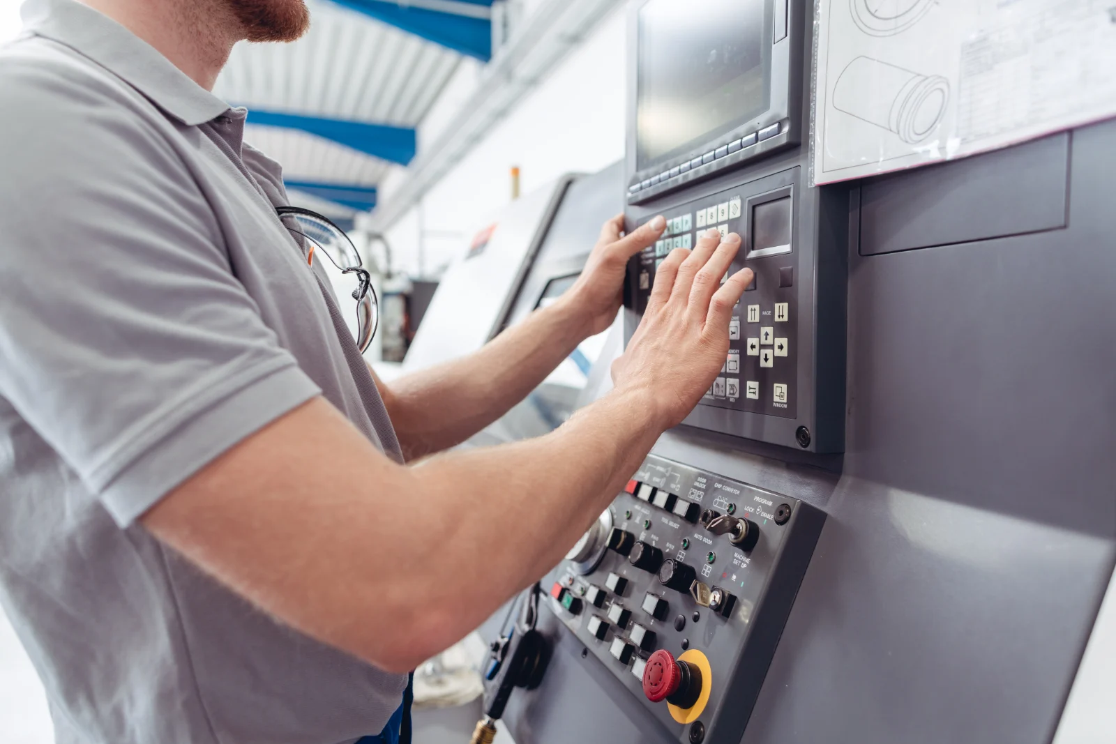 An operator entering a program at the control panel of a CNC machine tool.
