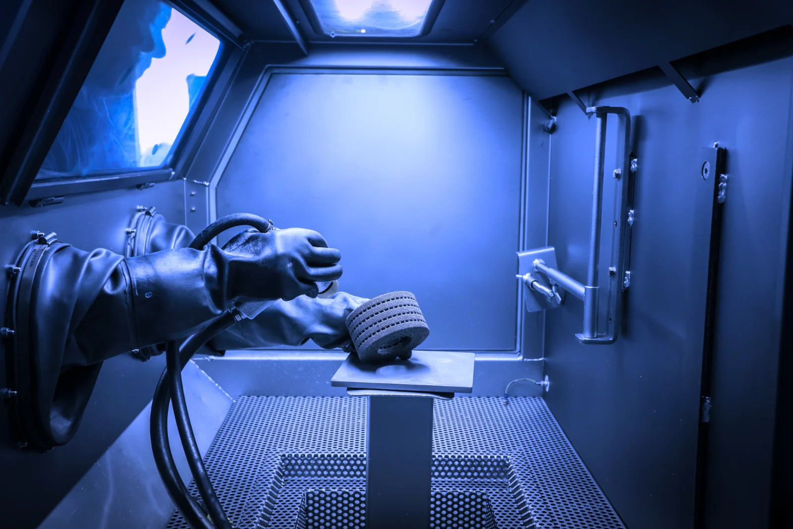 Operator using a glovebox to depowder a printed lattice part
