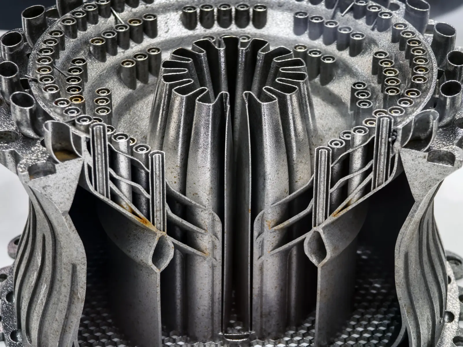 Sectioned metal component showing complex internal channels and tubes