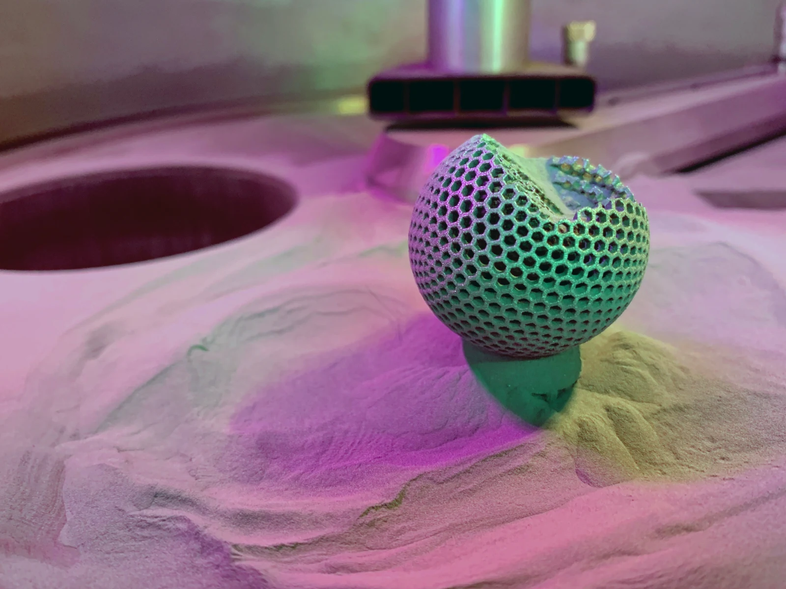 A printed metal sphere resting in the additive manufacturing powder bed