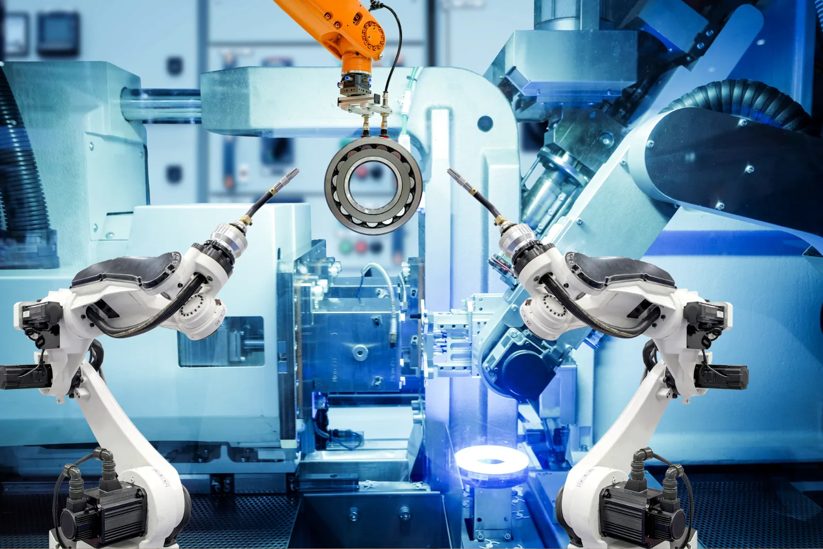 Robotic arms handling a bearing ring inside an automated machining cell