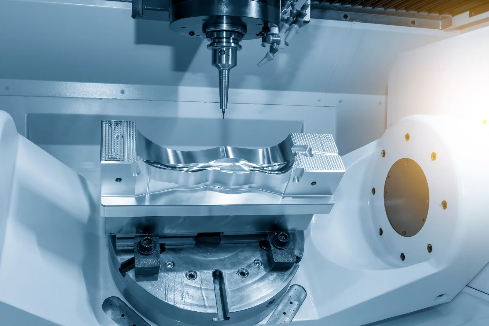 Five-axis milling machine cutting a contoured mould cavity