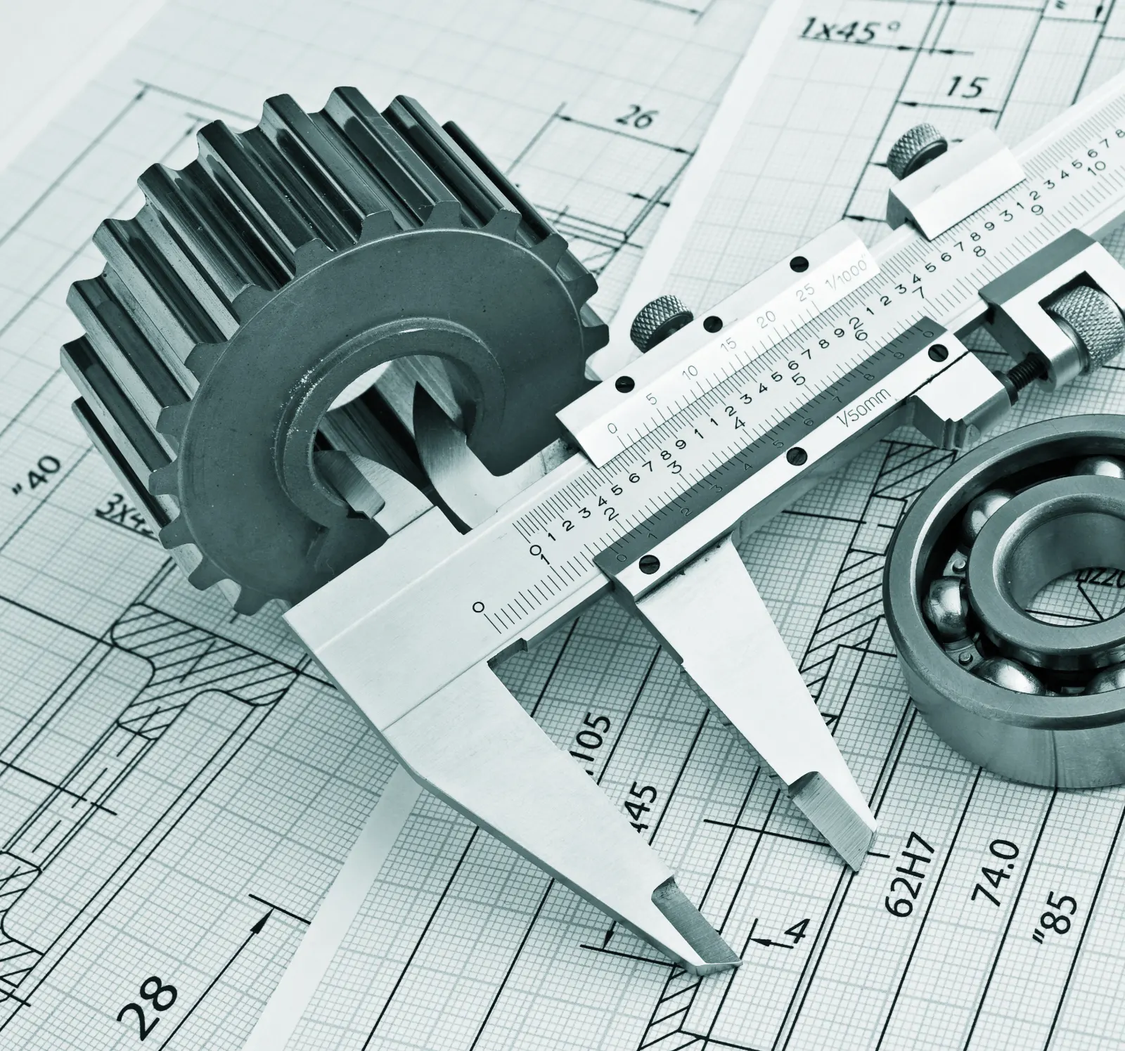 Vernier caliper measuring a steel gear on a dimensioned drawing
