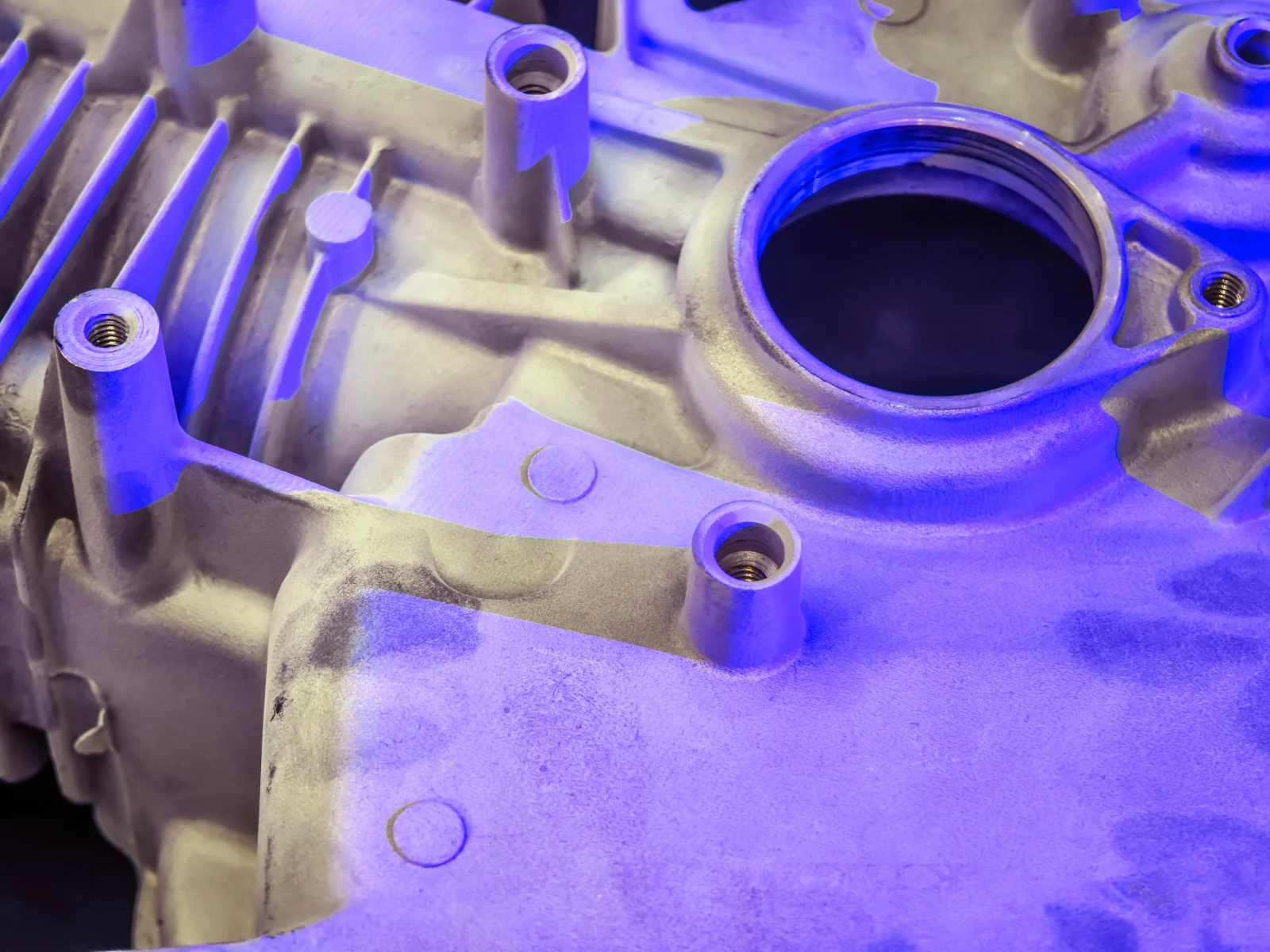Machined aluminium housing with threaded bosses under inspection lighting