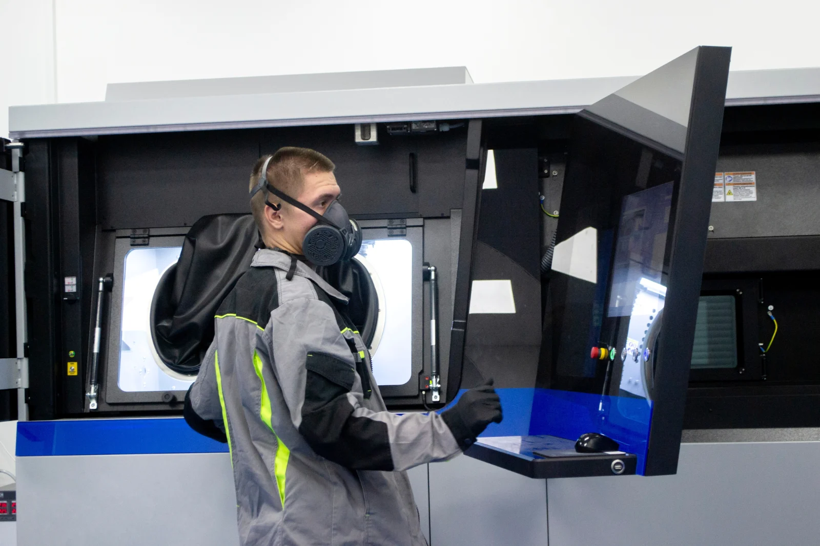 Operator in protective gear working at an open powder-bed printer