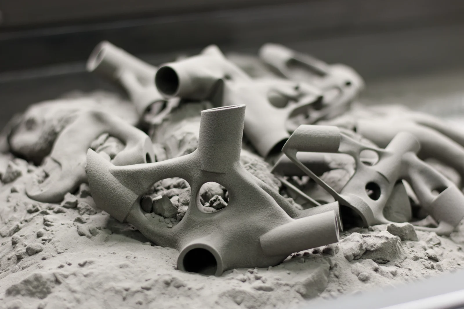 Lattice-braced printed parts resting in the powder bed before cleaning.