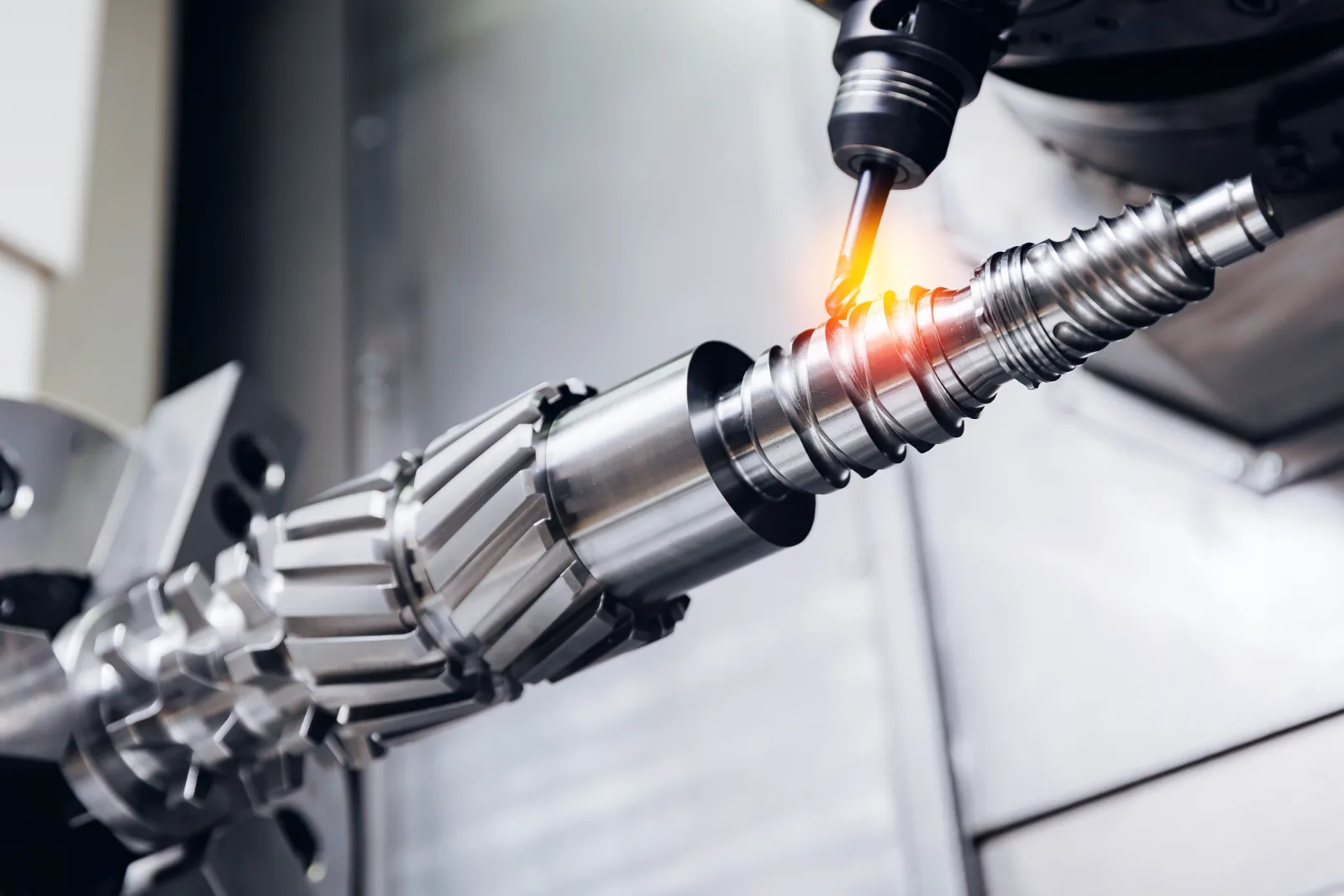 Turning tool machining a splined shaft with a glowing chip