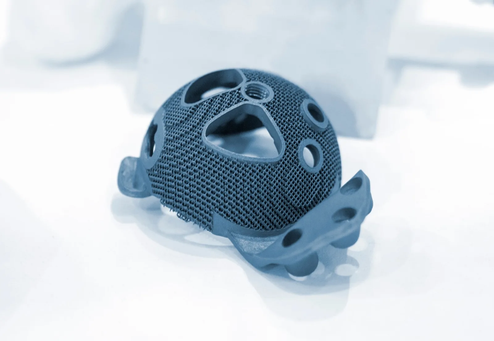 Printed titanium medical implant with a fine lattice surface on a white background
